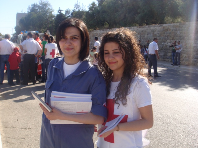 صبيتان بمقتبل العمر، مشرقتا الوجه، توزعان المطبوعات التي تحوي النصائح والتوجيهات للمواطنين