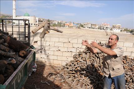 يحمّل كميات من الحطب في شاحنته - سامر الحسيني