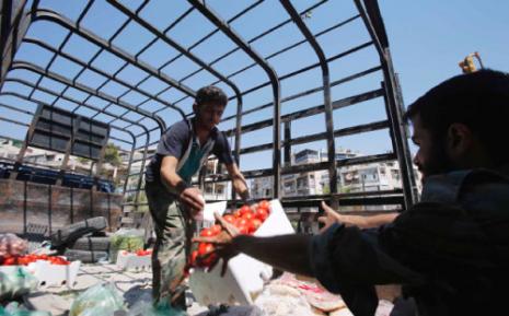 مقاتل من الجيش السوري الحر يوزع المؤونة في حلب (يوسف بودلال ــ رويترز)