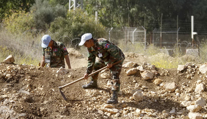 عنصران من الوحدة  الكمبودية يعملان على تنظيف حقل في سهل مرجعيون على الخط الازرق مقابل مستعمرة المطلة