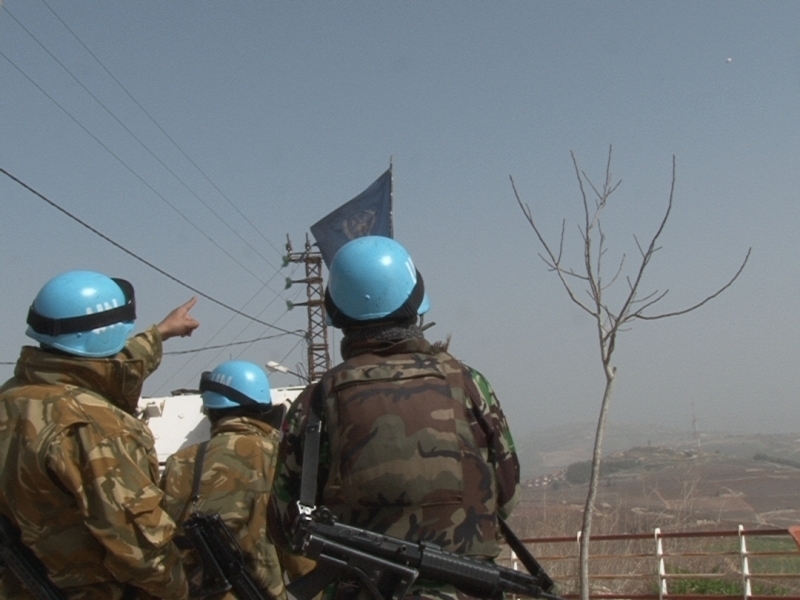 جنود دوليون يشيرون الى المنطاد الاسرائيلي في أعلى الصورة