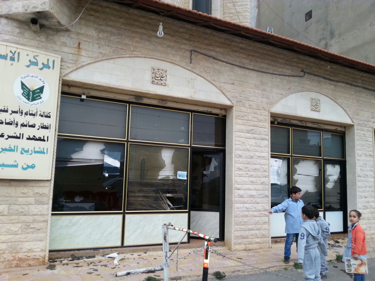 أولاد يشيرون الى مكان تحطيم الزجاج في مركز النور الخيري