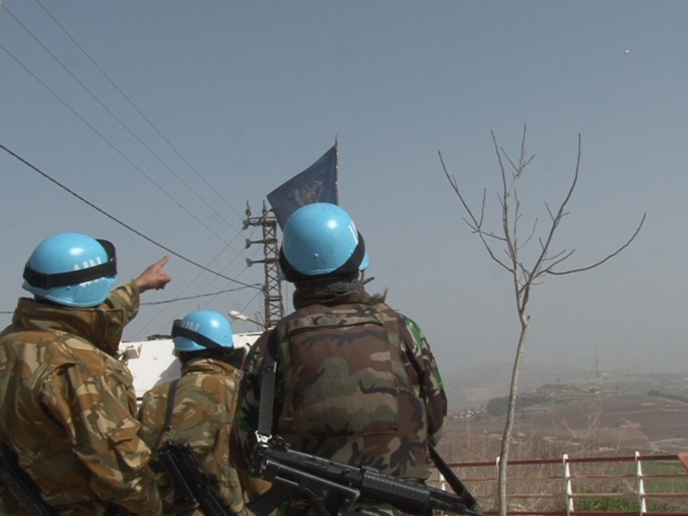 جنود دوليون قرب الخط الازرق يشيرون الى المنطاد الاسرائيلي في أعلى الصورة