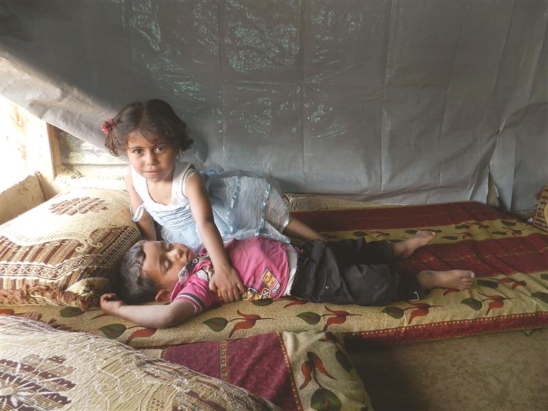 طفلة نازحة ترعى شقيقها في غياب والدتها (طارق أبو حمدان)