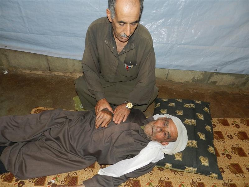 نازح يساعد نازح اغمي عليه في مخيم ابل السقي (طارق ابو حمدان)