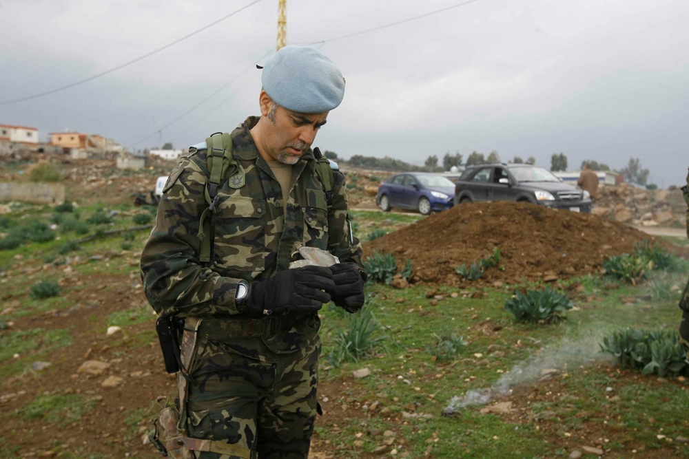 جندي دولي يعاين بقايا القذائف التي اطلقها العدو على الوزاني