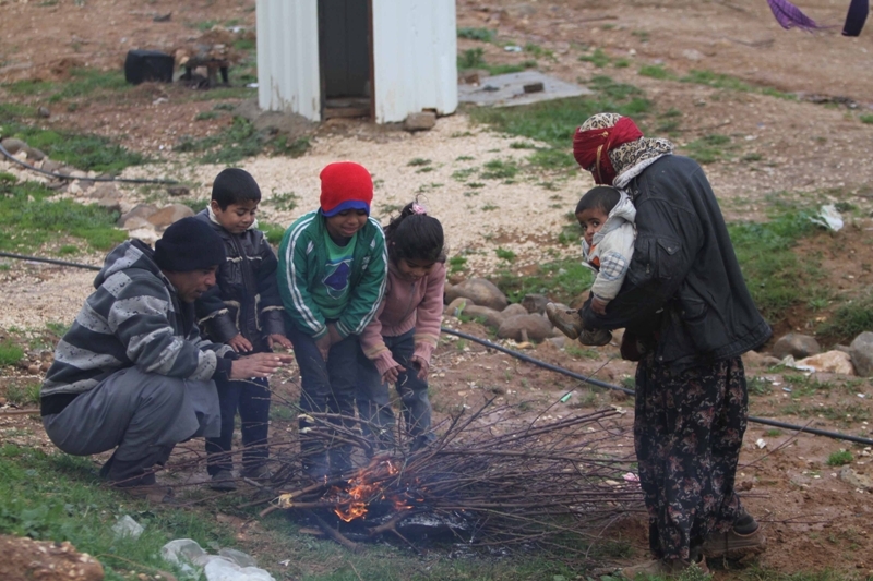 أطفال يجلسون قرب النار من شدة البرد