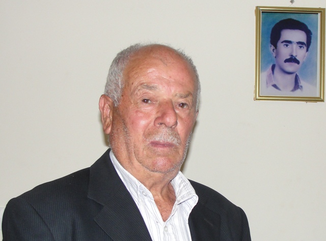 الحاج أبو محمود حسن الباشا، وخلفه رسم زيتي لإبنه الشهيد قاسم باشا