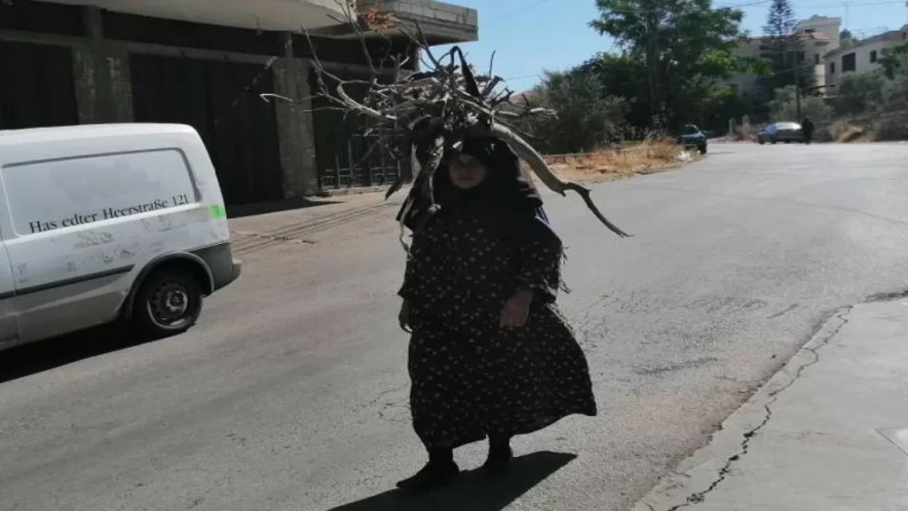 سيدة تنقل الحطب على رأسها