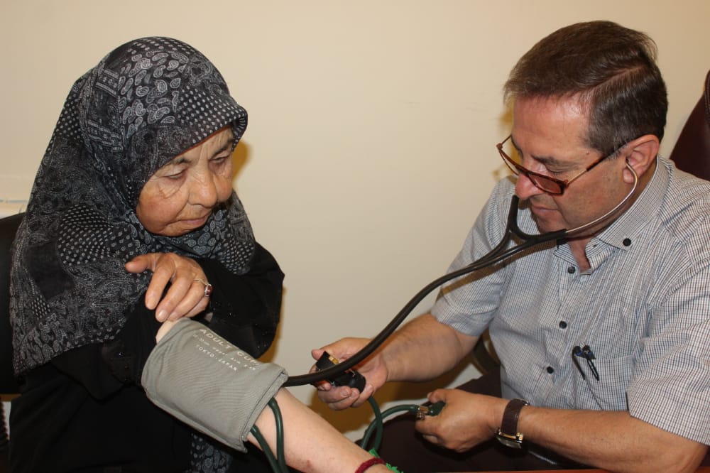 الدكتور نبيل خريس يولي كامل العناية بإحدى السيدات المسنّات في الخيام.. أرشيف