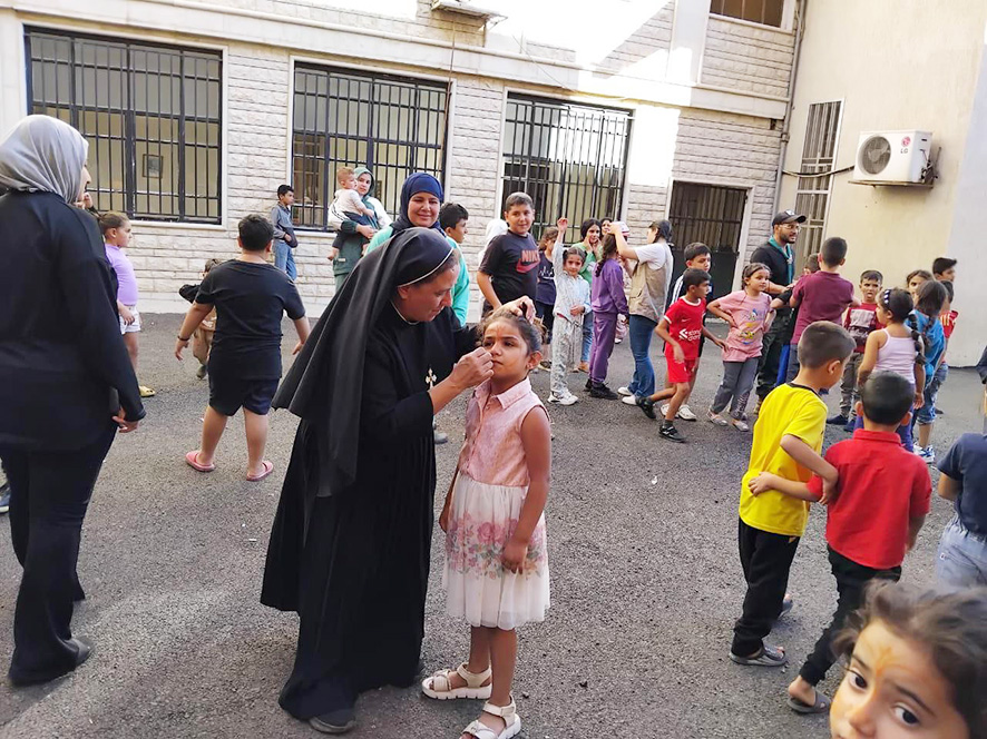 راهبة ترسم على وجه طفلة نازحة في ديرجبولة في البقاع الشمالي أثناء الحرب الأخيرة